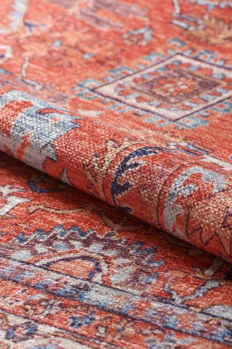 A close-up of the Mystral Kilim-Design Coral Washable Rug (LCC3015), featuring intricate geometric and floral patterns in red, blue, cream, and gold—ideal for high-traffic areas.