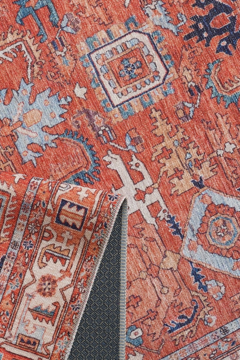 A close-up of the Mystral Kilim-Design Coral Washable Rug (LCC3015) shows red, blue, and cream geometric patterns. One corner is folded to reveal textured gray backing—ideal for high-traffic areas.