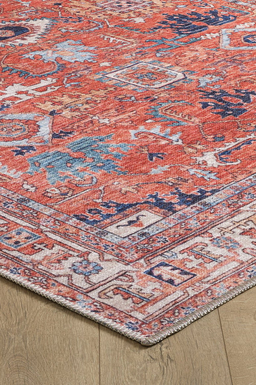 Load image 1 in gallery view. A close-up of the Mystral Kilim-Design Coral Washable Rug - LCC3015 (Custom Size) shows its rectangular, multicolored geometric and floral patterns in red, blue, and cream on a light wooden floor—ideal for high-traffic areas.