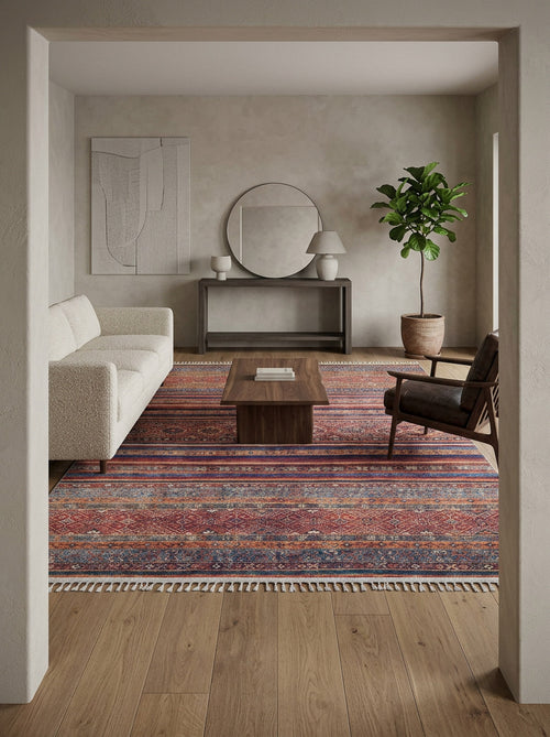 Load image 1 in gallery view. Red and blue striped rug with a distressed geometric pattern and fringe, styled in a modern living room.