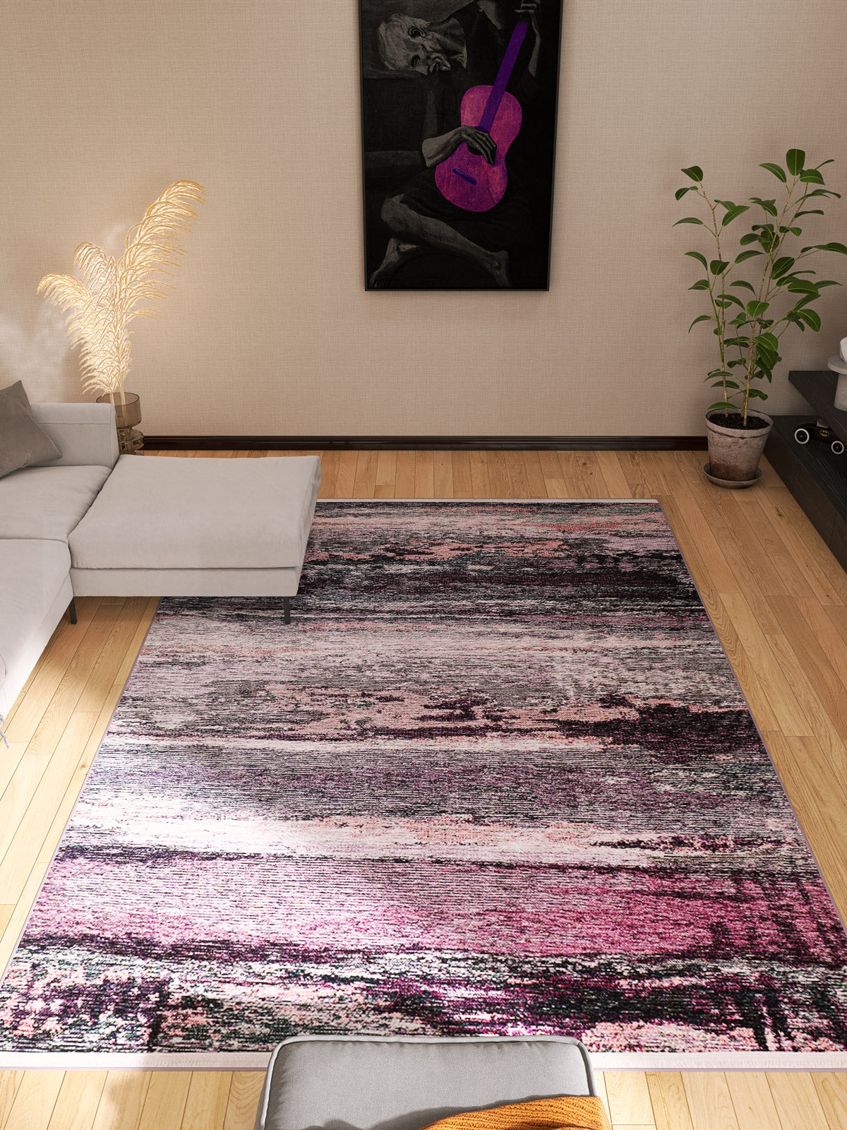 A modern living room with a light corner sofa, the Natural Brushed - Washable Rug - JR336 in purple for high-traffic areas, a potted plant, framed purple guitar artwork, and a tall vase with pampas grass on wooden flooring.