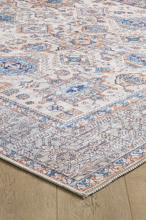Load image 1 in gallery view. The Nexa Bordered Beige Washable Rug (LCC3009) features cream and beige tones with blue, gray, and beige geometric and floral patterns, a decorative border, and a distressed vintage look on a flat woven surface.