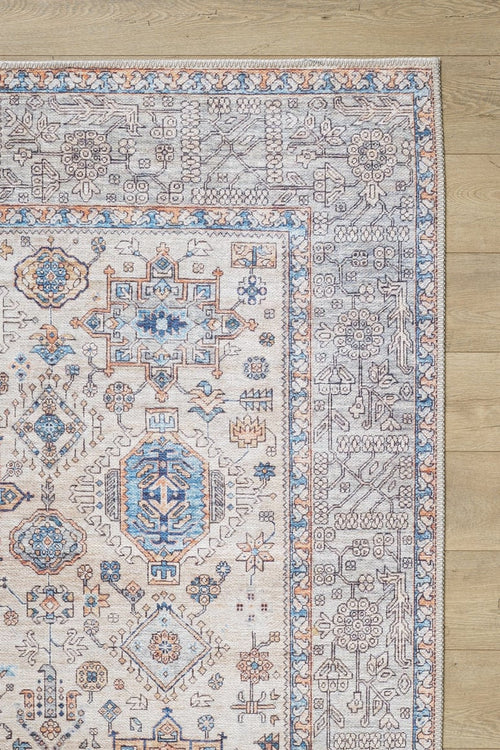Load image 1 in gallery view. A close-up of the Nexa Bordered Beige Washable Rug - LCC3009 (Custom Size) highlights its blue, orange, and gray geometric-floral patterns on a beige background—an ideal choice for high-traffic areas on light wood floors.