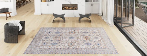 Load image 1 in gallery view. A bright, modern living room with light wood floors, a Nexa Bordered Beige Washable Rug - LCC3009 (Custom Size), a black woven chair, curved gray stools, a fireplace, and large windows—ideal for high-traffic areas.
