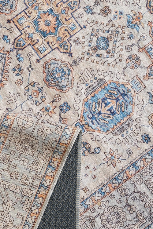Load image 1 in gallery view. A close-up of the Nexa Bordered Beige Washable Rug - LCC3009 (Custom Size) shows intricate blue, orange, and beige geometric and floral patterns. A folded corner reveals its textured non-slip backing—ideal for high-traffic areas.