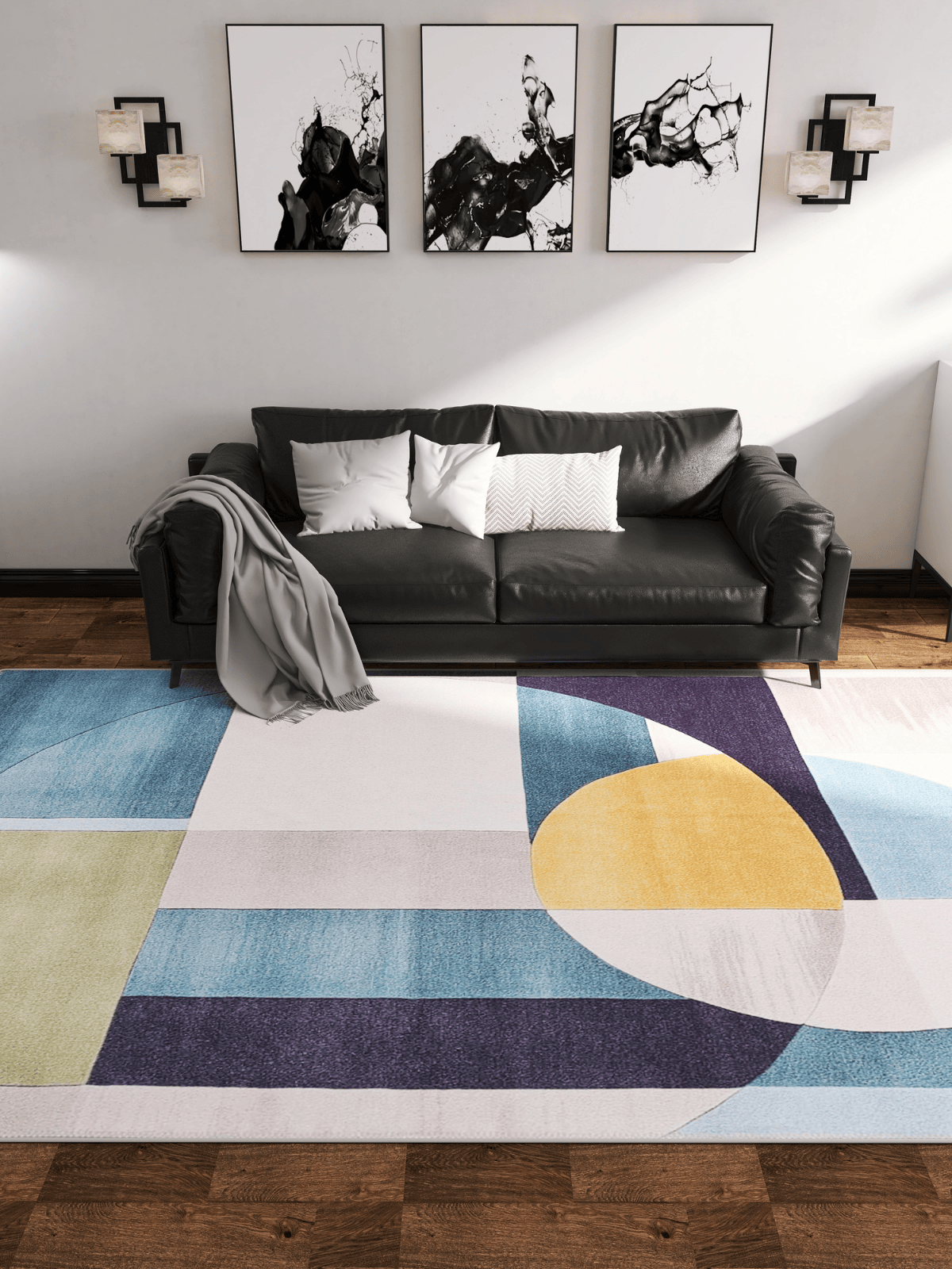A modern living room features a black sofa, white and gray pillows, abstract black-and-white artwork, and the Nexus Geometric Contemporary Washable Rug - MDJ006 with vibrant yellow, blue, green, and purple shapes—ideal for high-traffic wood floors.