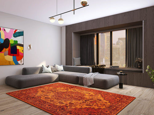 Load image 1 in gallery view. Modern living room featuring a large gray sectional, the Noble Odyssey - Washable Rug - JRN1012 (Custom Size) in orange medallion, colorful abstract wall art, city views through wide windows, minimalist decor, neutral tones, and wood flooring.
