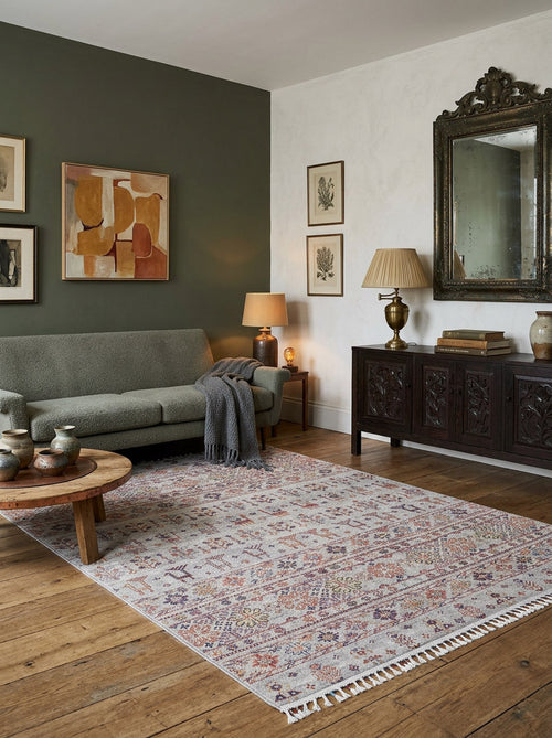 Load image 1 in gallery view. Light grey rug with a multi-colored traditional floral pattern and tasseled edges, styled in a living room.