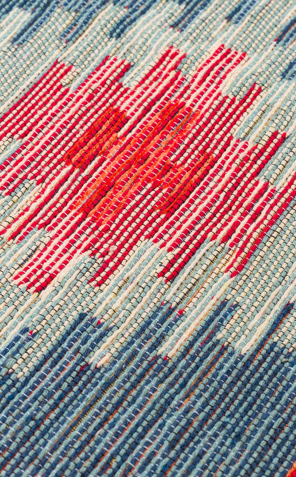 Close-up of the Ocean Form - Washable Reversible Kilim (NMD04) showcasing a woven blue and turquoise tribal pattern with a central red area accented by irregular white stripes.