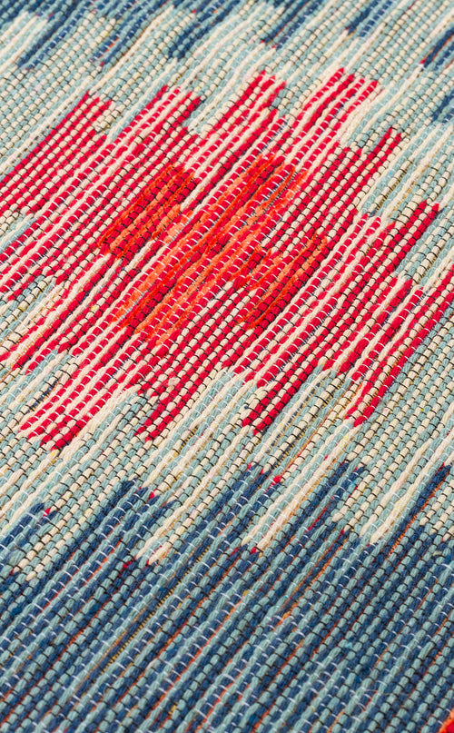 Bild 1 in Galerieansicht laden. Close-up of the Ocean Form - Washable Reversible Kilim (NMD04) showcasing a woven blue and turquoise tribal pattern with a central red area accented by irregular white stripes.