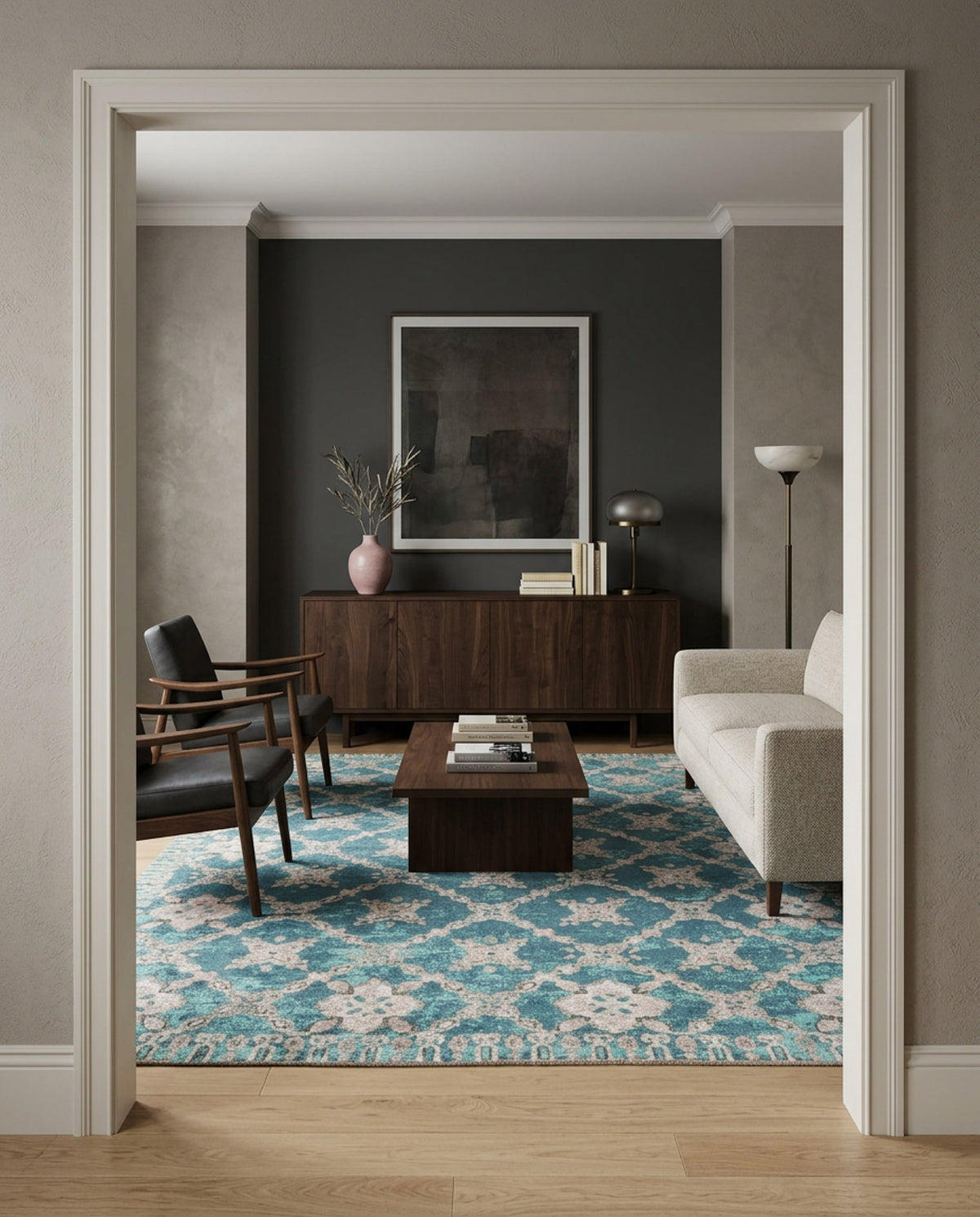 A modern living room with a beige sofa, two dark armchairs, a wooden coffee table, and the Ocean Trellis Area Rug APX1942. A dark accent wall displays large framed art above a wooden sideboard decorated with accents.