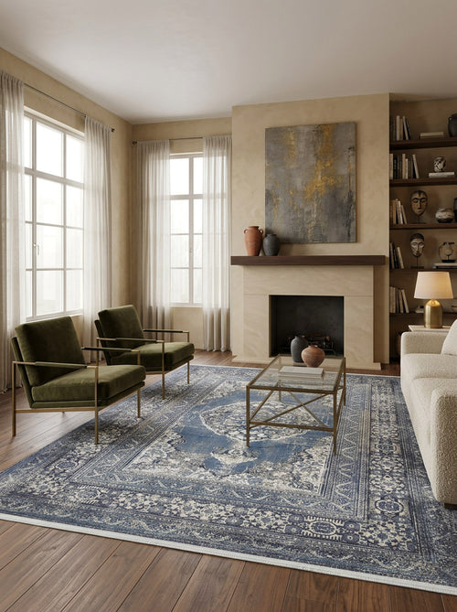 Load image 1 in gallery view. A modern living room with large windows, sheer curtains, two green armchairs, a white sofa, the Opulent Beauty - Washable Rug - JR1932 ideal for high-traffic areas, a glass coffee table, fireplace, and built-in shelves adorned with art and decor.