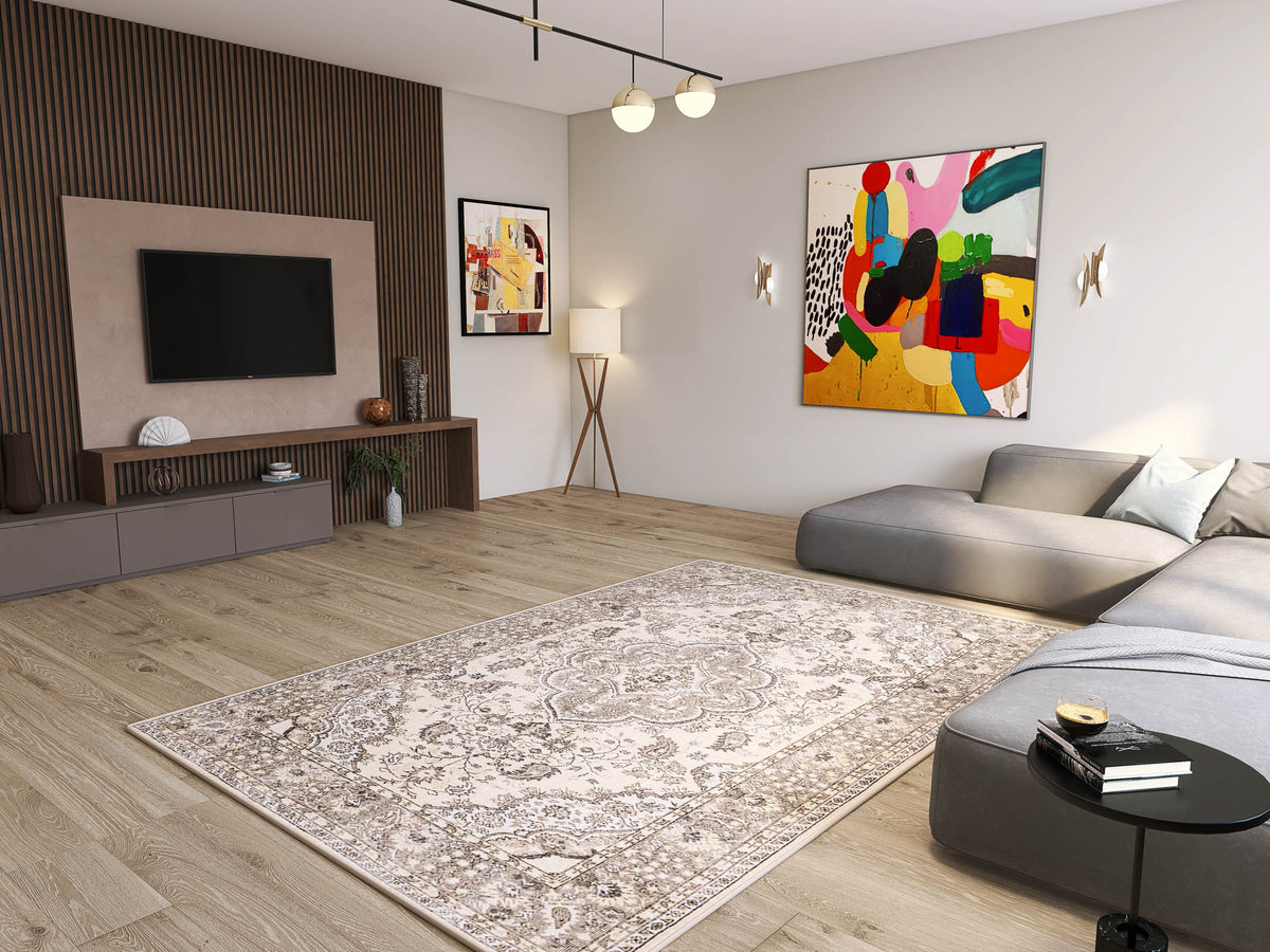 Modern living room with the Opulent Mirage - Washable Rug (JRN1008) in a subtle medallion design, gray sectional sofa, TV on wood-paneled wall, abstract art, floor lamp, light wood flooring, and minimalist decor.