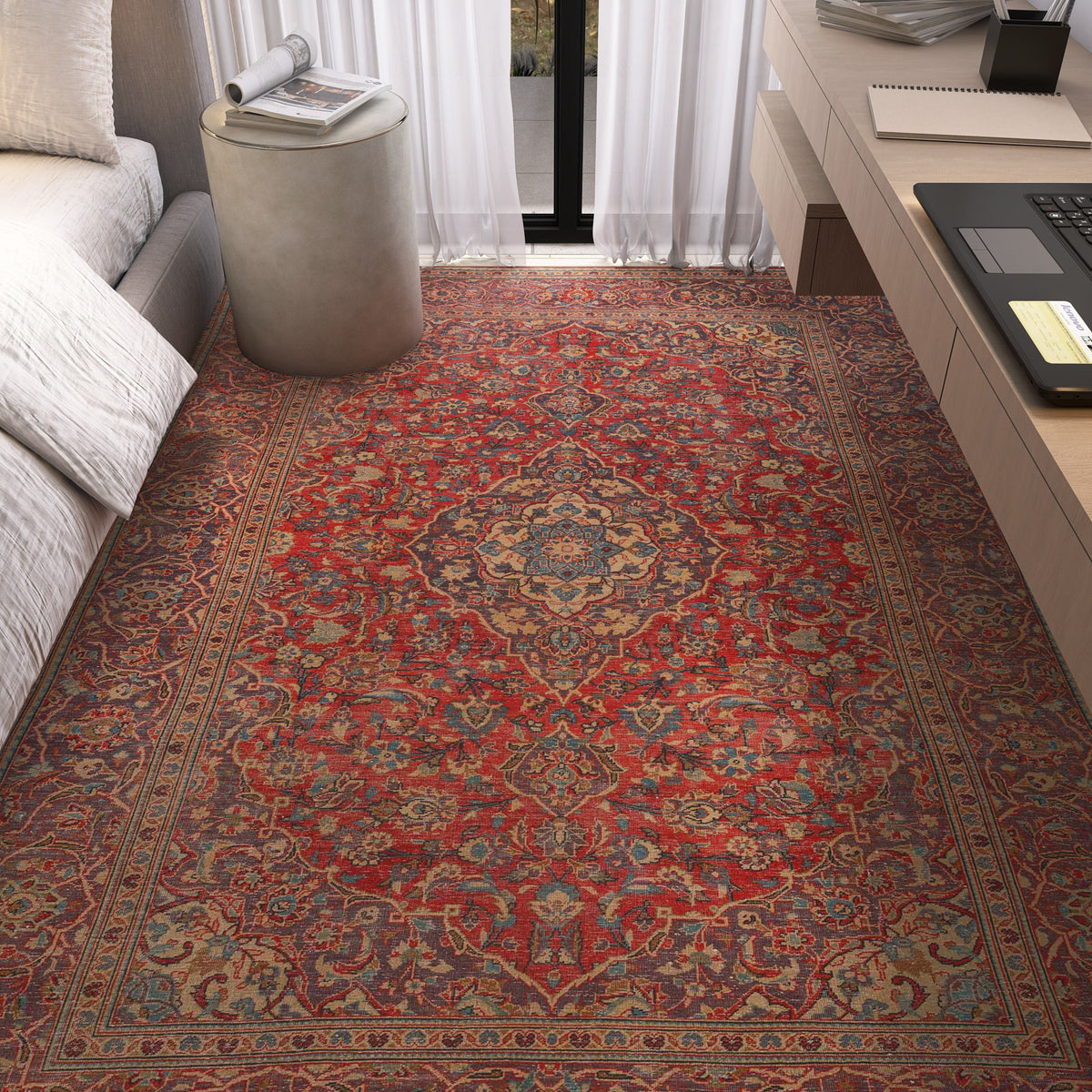 The Palatial Grace - Washable Rug - JRN1021 (Custom Size), featuring intricate vintage medallion and floral patterns, covers the floor beside a bed, near a round ottoman and desk with a laptop in a sunlit bedroom.