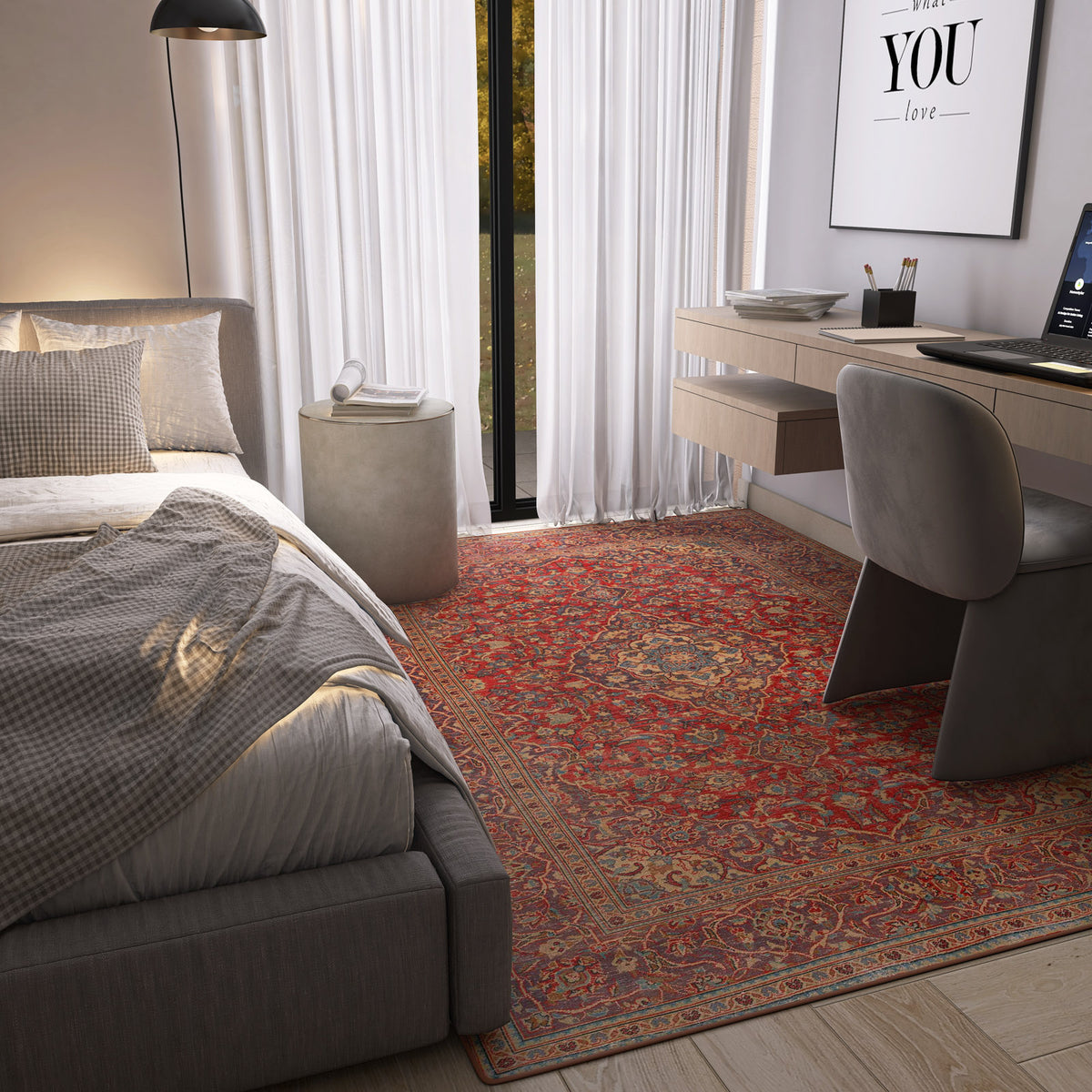 A cozy bedroom with a gray bed, checkered bedding, the Palatial Grace - Washable Rug - JRN1021 (Custom Size) in red, a floating desk with a computer, modern chair, and large windows with sheer white curtains letting in natural light.
