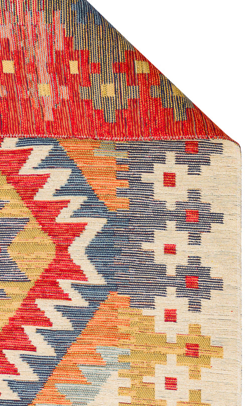 Load image 1 in gallery view. A close-up of the Pastel Grid - Washable Reversible Kilim (NMD09) shows its vibrant geometric patterns in red, blue, yellow, and cream. A folded corner reveals the rug’s detailed design and texture.