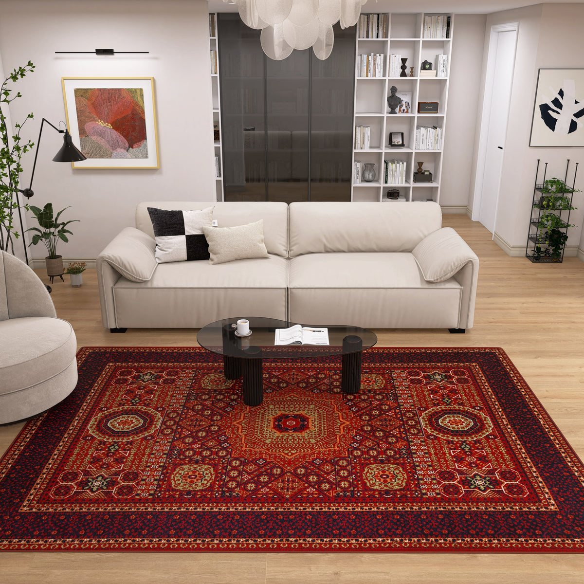 A modern living room features a light beige sofa, black oval coffee table, and the Patch Bloom - Kilim - BHR10 rug on wooden floors. White shelves with books decorate the back wall, while lush plants fill the corners for a cozy touch.