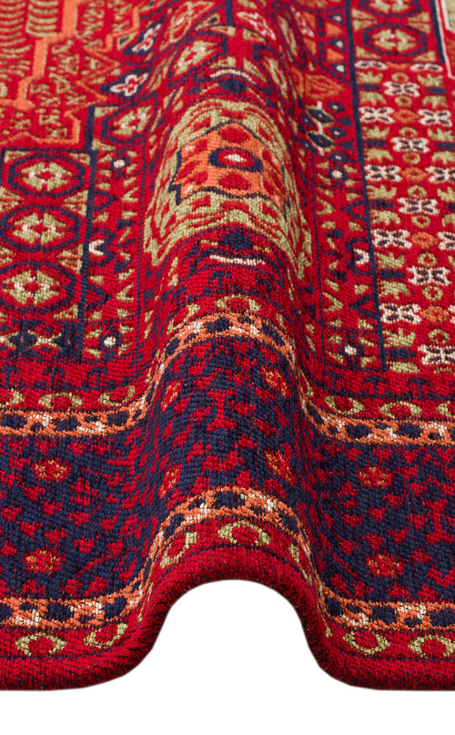 Load image 1 in gallery view. A close-up of the Patch Bloom - Kilim - BHR10 shows its red and dark blue geometric and floral patterns with a visible wave in the fabric near the bottom.
