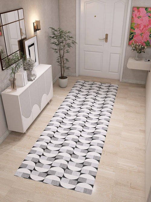Load image 1 in gallery view. A bright, minimalist hallway with light wood floors features the Patina Bloom - Washable Rug - JRN50 as a geometric runner, paired with a white sideboard, potted plant, wall art, and a white door with gold hardware.