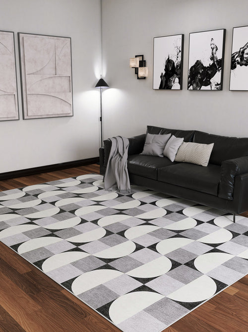 Bild 1 in Galerieansicht laden. Modern living room with a black sofa, gray and white pillows, and a blanket. Abstract art decorates the walls, while the Patina Bloom - Washable Rug - JRN50 adds geometric style to the hardwood floor. Floor lamp and wall lights brighten the space.