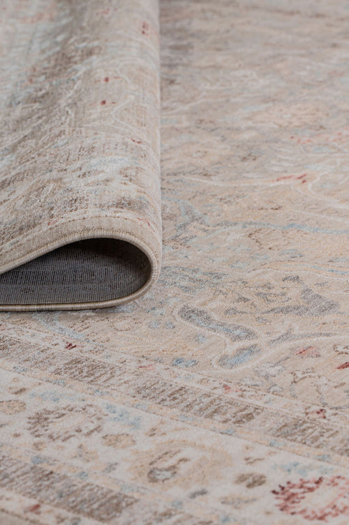 Load image 1 in gallery view. A close-up of the Pearl Oushak - Area Rug - APX2931 in beige, featuring subtle blue and red accents. One edge is slightly lifted to reveal the backing, highlighting its texture and intricate vintage-inspired design.
