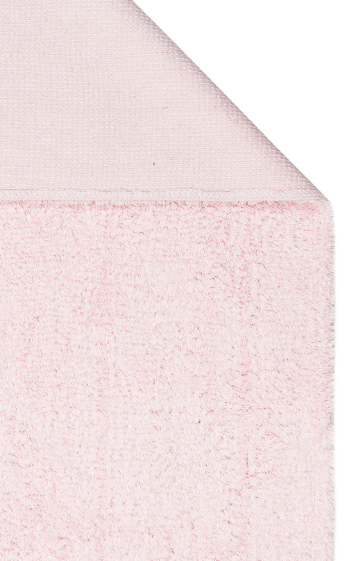 Load image 1 in gallery view. A close-up of the Powder Calm - Washable Shaggy - CBNPLAIN shows its soft, fluffy texture and smooth, folded corner—ideal as a washable shaggy rug for a modern bedroom.
