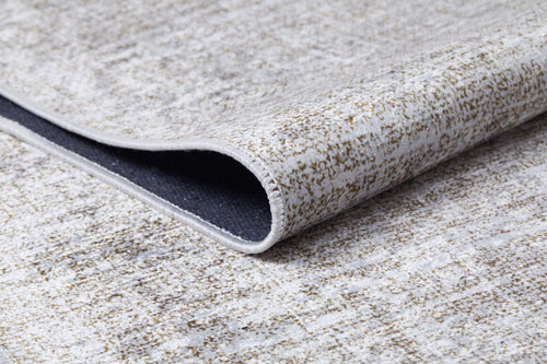 Load image 1 in gallery view. A close-up of the Pure Bliss - Washable Rug - JR745 (Custom Size) in cream and beige, featuring a subtle pattern and lifted edge to reveal its dark, non-slip backing—perfect for allergy-sensitive homes.