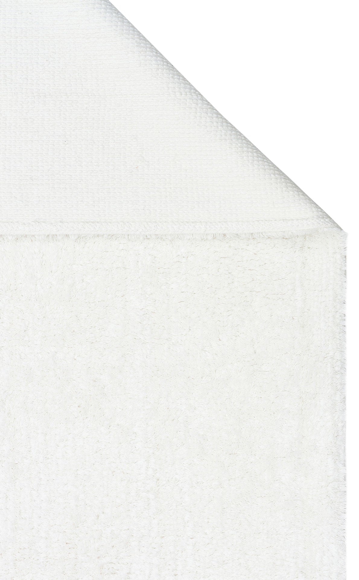 A close-up of the Pure Thread - Washable Shaggy - CBNPLAIN white cotton rug, with one corner folded over to highlight its textured front and smoother back.