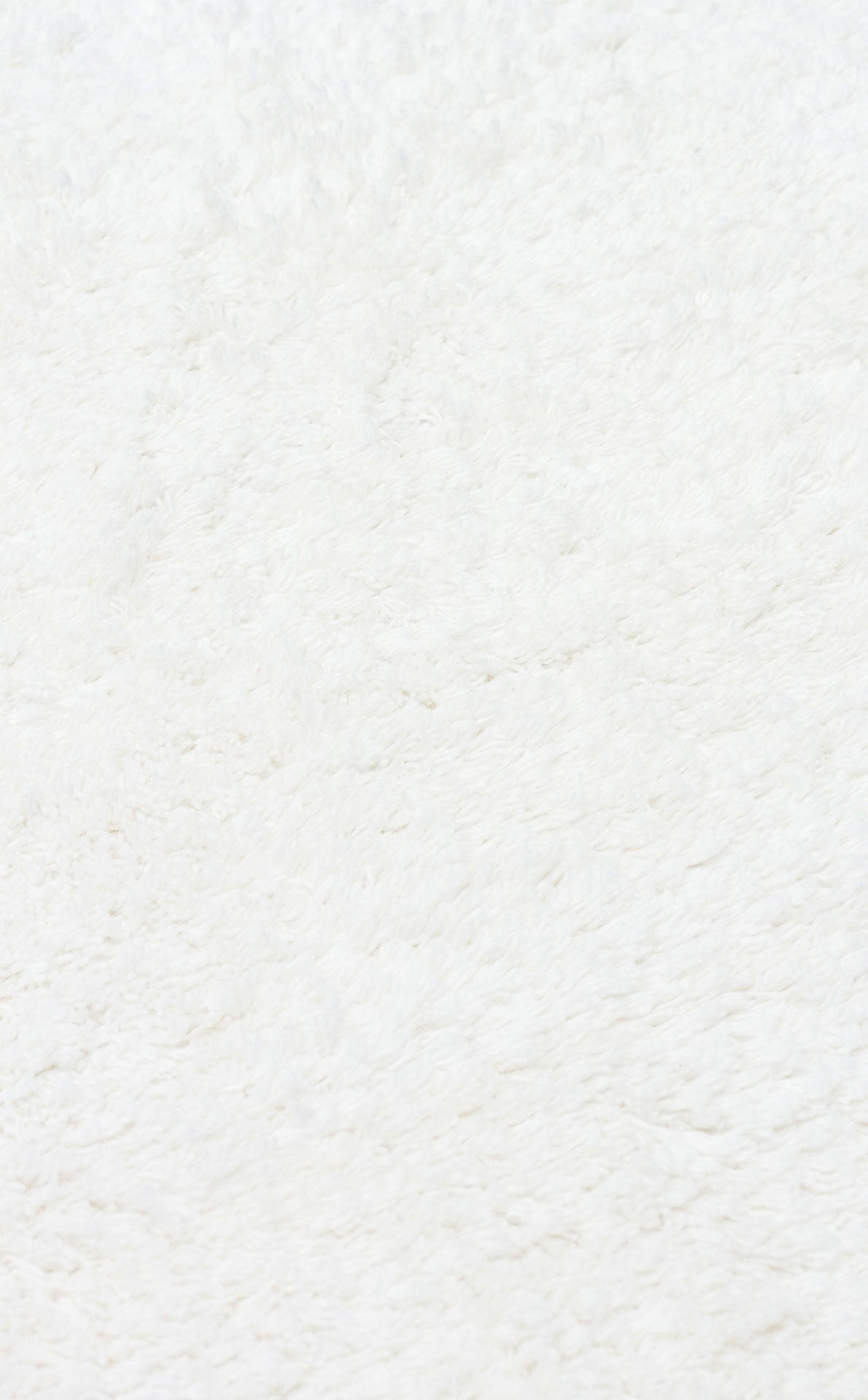 Close-up of the Pure Thread - Washable Shaggy - CBNPLAIN rug, showcasing its soft, white, fluffy texture and plush feel. The clean, even surface features subtle shadows, highlighting this cozy machine-washable cotton rug.