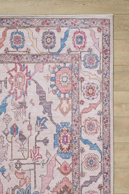 Load image 1 in gallery view. A close-up of the Quasar Traditional Washable Rug - LCC3024 shows its pink, blue, and beige geometric and floral patterns on a light wooden floor. This washable rug combines charm with practicality for any space.