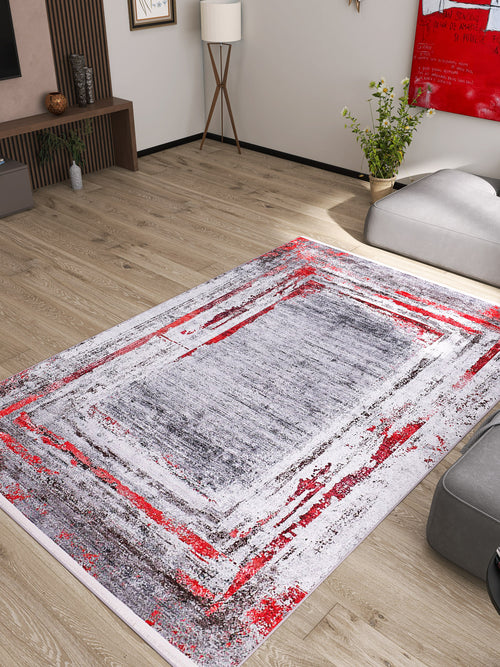 Load image 1 in gallery view. A modern living room with light wood flooring, gray furniture, and the Refined and Timeless - Washable Rug - JR1500 in abstract red, gray, and white—ideal for high-traffic, allergy-friendly spaces—plus a potted plant, floor lamp, and vibrant artwork.