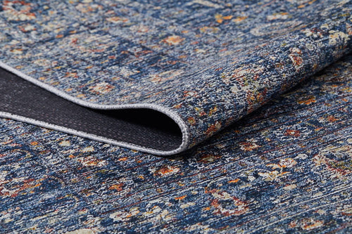 Load image 1 in gallery view. A close-up of the Regal Splendor - Washable Rug - JR1017 (Custom Size) in blue, with a folded corner showing its dark underside. The rug’s distressed design features blue, yellow, orange, and white speckles—ideal for high-traffic areas.