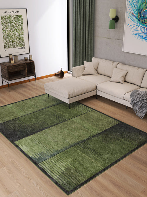 Load image 1 in gallery view. Modern living room with a beige sectional sofa, wood flooring, green curtain, wall art, a side table with books, and the Regal Texture - Washable Rug - JRN34 in green and black geometric print—perfect for high-traffic areas and minimalist neutral decor.