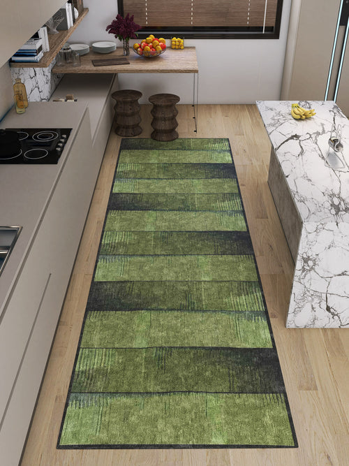 Load image 1 in gallery view. A modern kitchen with light wood floors, marble countertops, and a Regal Texture - Washable Rug - JRN34 (Custom Size) in green for high-traffic areas. Two wooden stools sit by the counter, while plants and fruit freshen up the space.