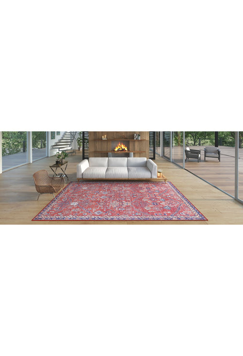 Load image 1 in gallery view. A modern living room features a white sofa, fireplace, wood coffee table, woven chair, and a Rhapsody Authentic Red Washable Rug - LCC3033 (Custom Size), perfect for high-traffic areas on light wood floors. Trees and patio furniture are visible outside.