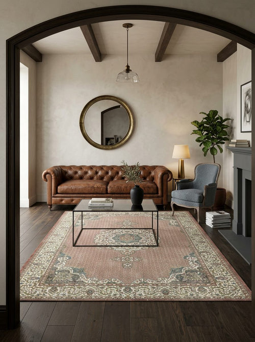 Load image 1 in gallery view. Dusty rose traditional rug with a central medallion and ornate border, styled in a living room with leather furniture.