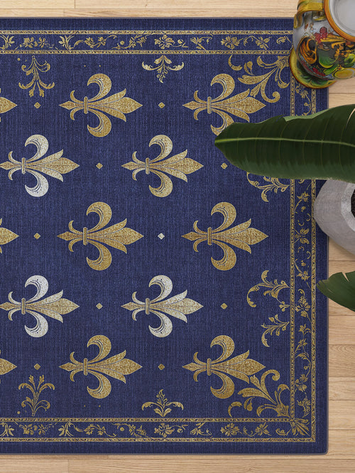 Load image 1 in gallery view. The Royal Fleur - Washable Rug - JRS016 (Custom Size) features a blue base with gold and silver fleur-de-lis and gold border details. Shown near a green plant and decorative object; perfect for high-traffic areas.
