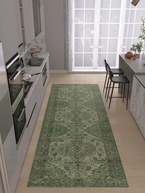 Load image 1 in gallery view. A modern kitchen with light wood floors features the Royal Vinework - Washable Rug - JRN1009 in green. White cabinets, built-in appliances, a sink, and a breakfast bar with two black stools sit by large windows.