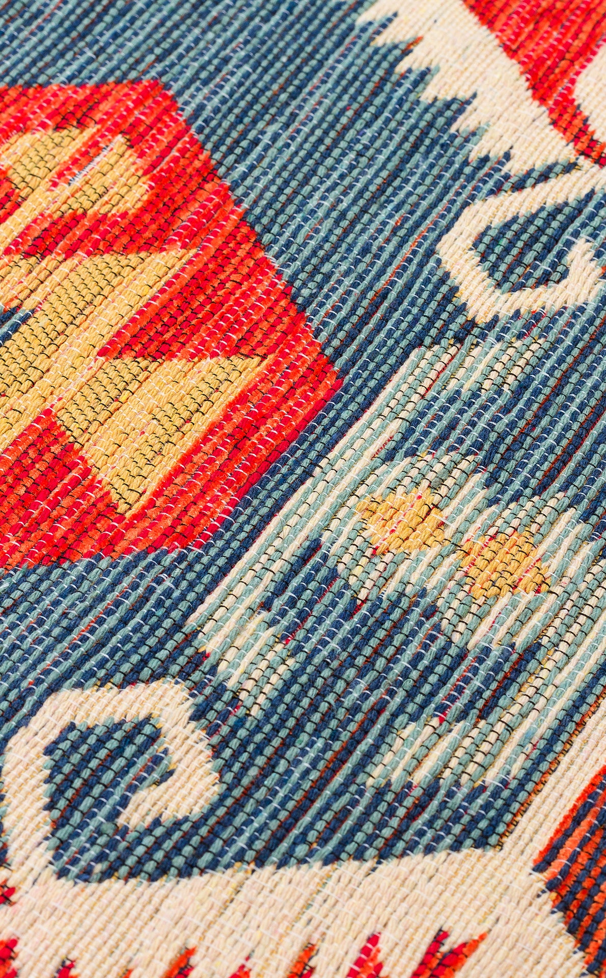 Close-up of Ruby Grain - Kilim - NMD06 featuring a geometric tribal pattern in red, blue, white, and yellow with zigzag and wave shapes and two small yellow stars on a blue background.