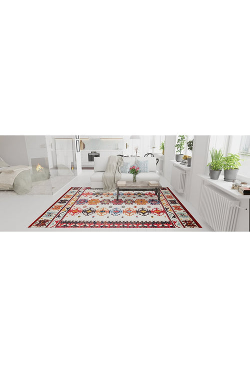 Load image 1 in gallery view. A bright living room with white walls and furniture features the Rustic Refrain - Washable Rug - JR149, green plants on the windowsills, a fireplace in the background, and a cushioned bench with a light throw blanket centered on the rug.