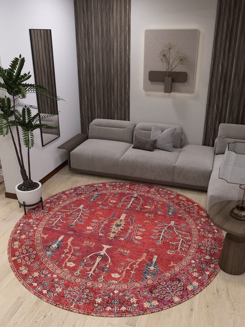 Load image 1 in gallery view. A modern living room features a gray sectional sofa, the Rustic Retreat washable rug (JR5095, custom size) in red—ideal for high-traffic areas—a potted plant, wooden accents, and minimalist wall art with mirrors.