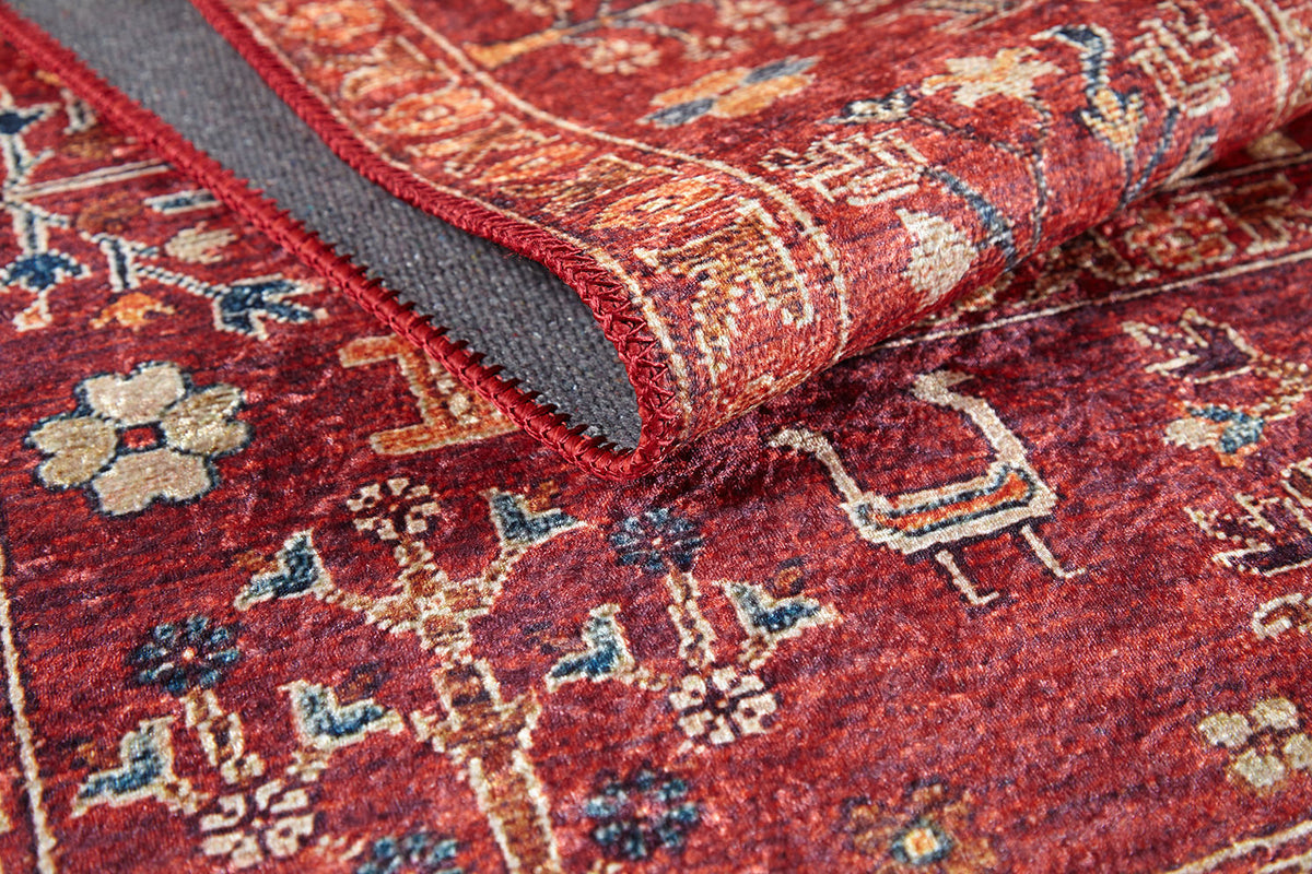 A close-up of the Rustic Retreat - Washable Rug - JR5095 (Custom Size) shows its red floral and geometric pattern, folded edge revealing a textured gray underside and stitched border—perfect for high-traffic areas.