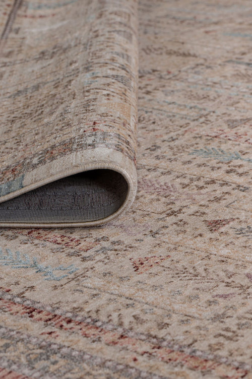Load image 1 in gallery view. Beige area rug with a distressed traditional pattern in muted red, blue, and grey, shown with a corner folded over.