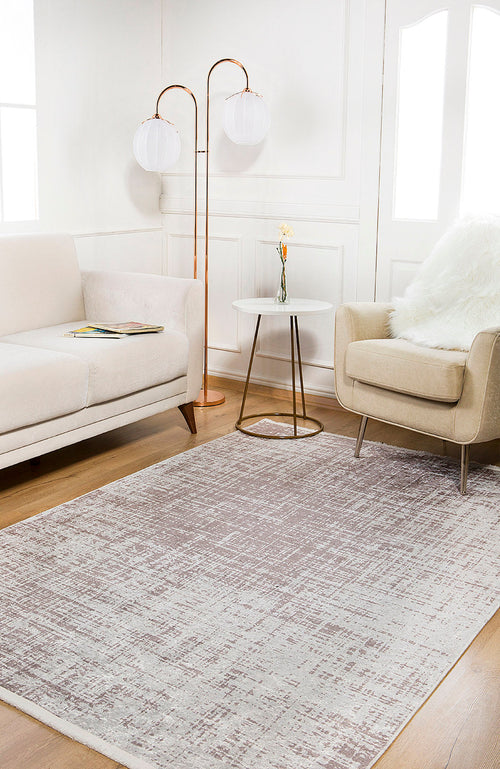 Bild 1 in Galerieansicht laden. A modern living room with a beige sofa, light armchair with a white fur throw, small round side table with a flower vase, two globe floor lamps, and the Sea Spray - Washable Rug - JR847 (Custom Size) in gray over wood flooring.