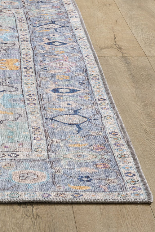 Load image 1 in gallery view. A close-up of the Seraphix Pastel Bordered Washable Rug - LCC3011 shows its rectangular, pastel blue design with a decorative border on light wood flooring—perfect for high-traffic areas with soft beige and pink intricate details.