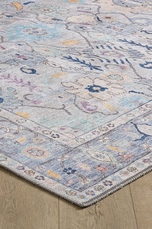 Bild 1 in Galerieansicht laden. A close-up of the Seraphix Pastel Bordered Washable Rug - LCC3011 (Custom Size) shows blue, purple, yellow, and beige accents on a light background, ideal for high-traffic areas and displayed on a wooden floor.