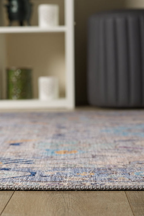 Bild 1 in Galerieansicht laden. A close-up of the Seraphix Pastel Bordered Washable Rug - LCC3011 (Custom Size) on a wooden floor, with a white shelf, candles, green glass container, and gray ottoman—ideal for high-traffic areas.