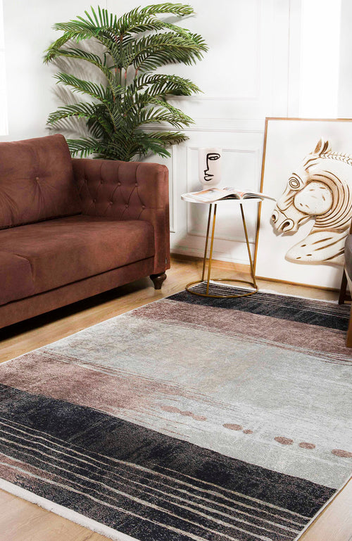 Load image 1 in gallery view. A modern living room with a brown sofa, gold and white side table, potted plant, large abstract horse artwork on the floor, and the Serene Swirls - Washable Rug - JR952 (Custom Size) in neutral tones—ideal for high-traffic spaces.
