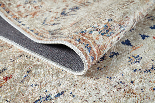 Load image 1 in gallery view. A close-up of the Shangri-La - Washable Rug - JR5042 (Custom Size) in cream and beige shows its lifted corner, revealing a textured gray underside and stitched edge. The abstract blue, red, and tan surface suits high-traffic areas.