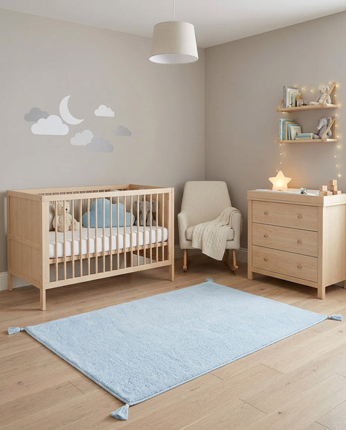 Load image 1 in gallery view. Solid light blue rug with corner tassels, styled in a neutral nursery with light wood furniture.